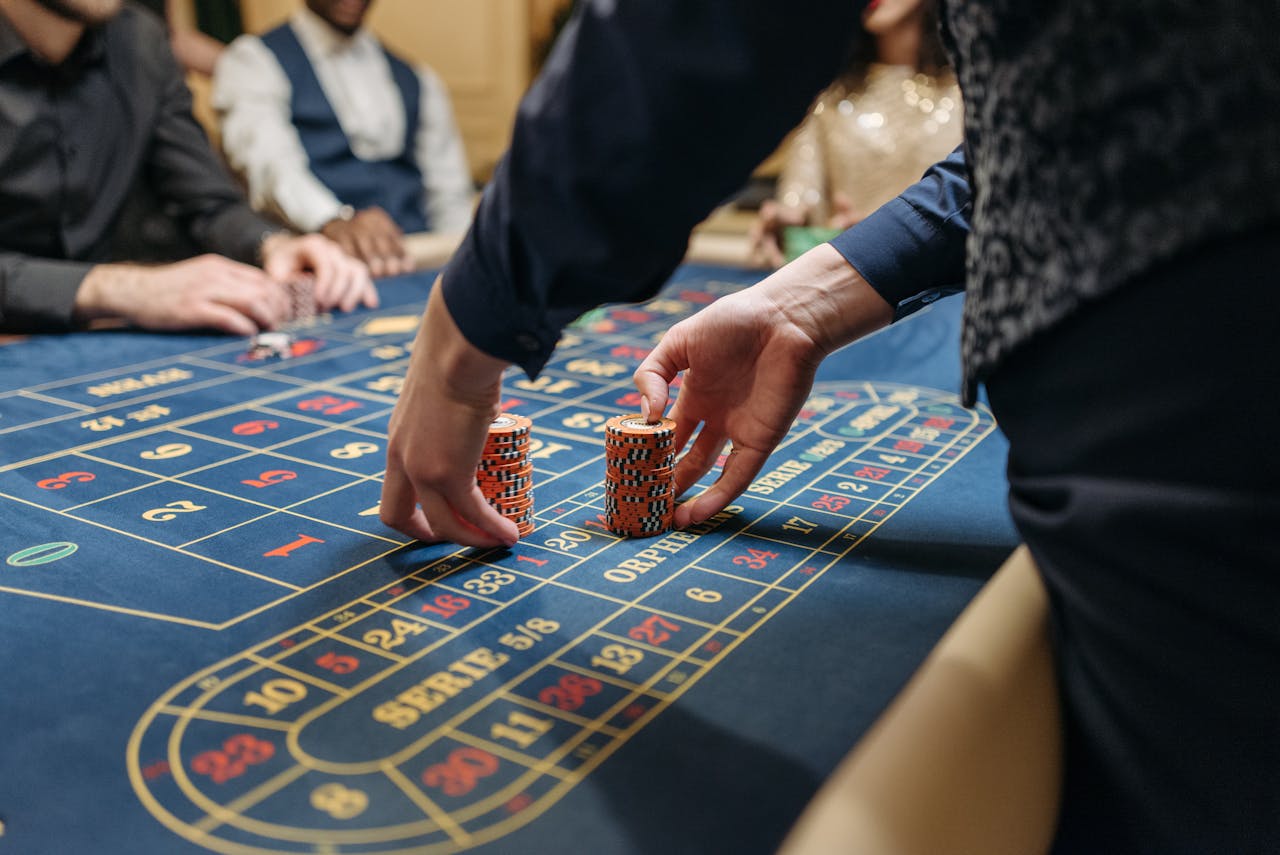 Close-up of players placing poker chips on a blue roulette table in a casino setting.